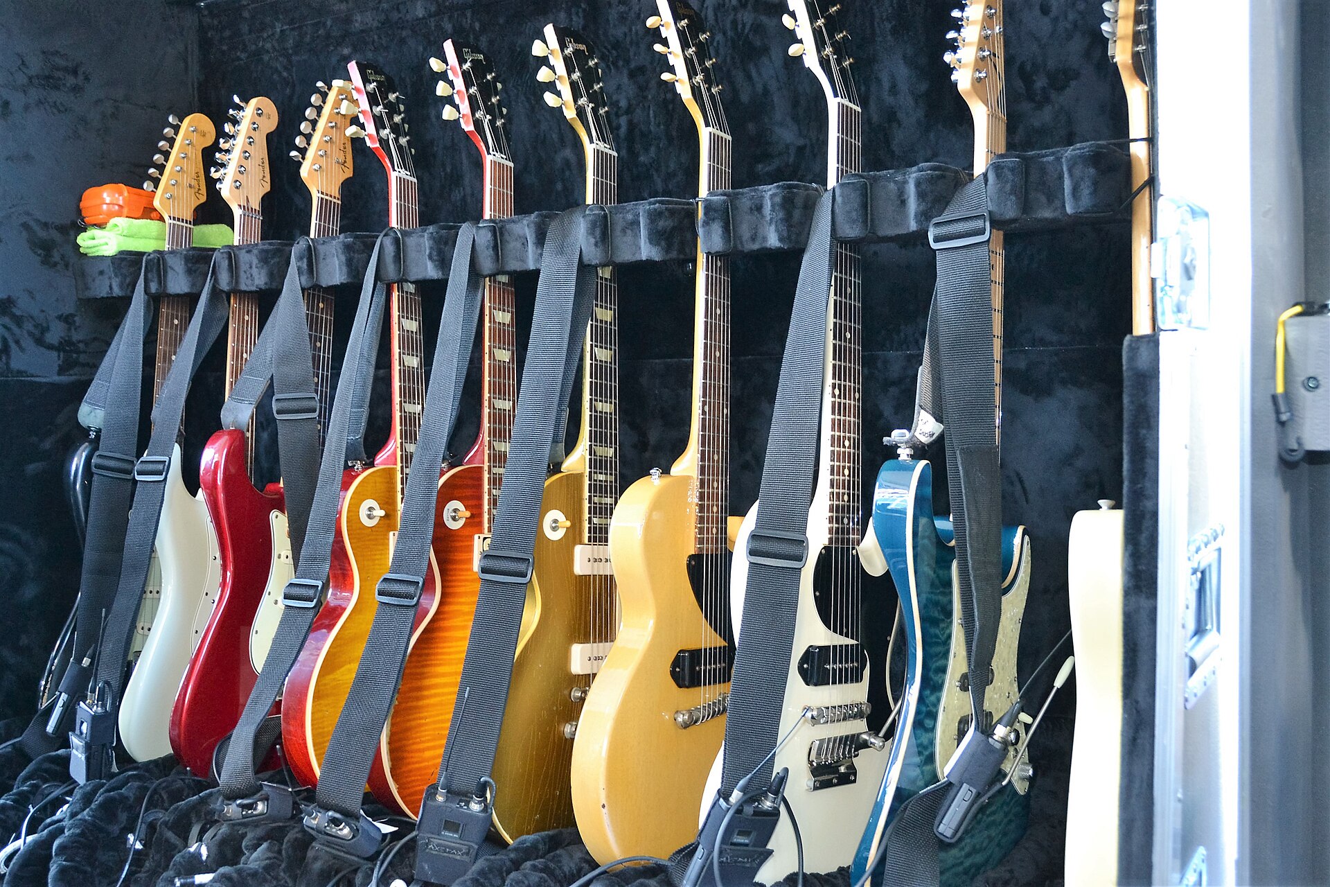 A backstage collection of electric guitars arranged together on instrument stands